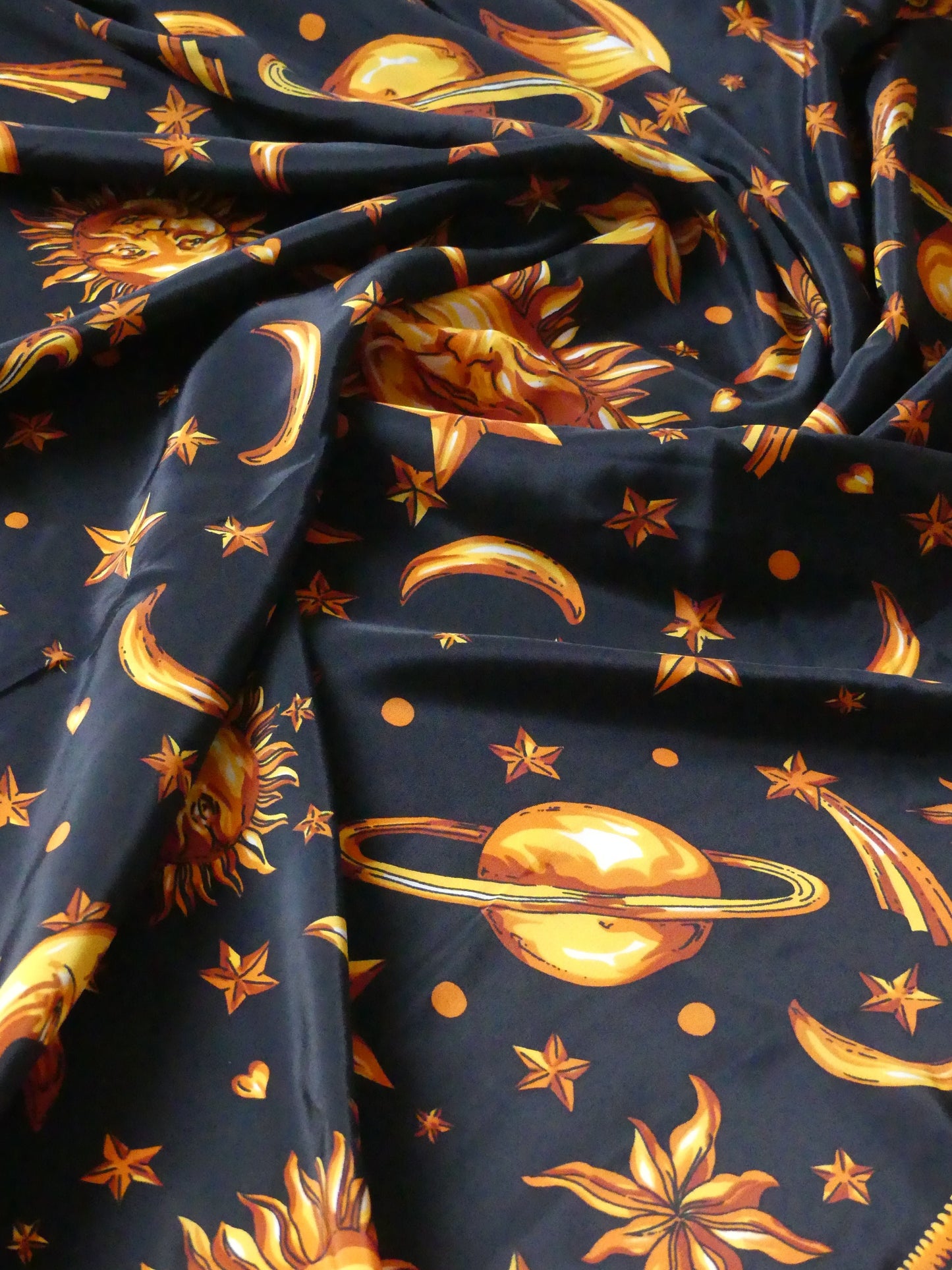 Elegant astrology silk scarf in black with golden celestial suns, stars, and planets, made in Paris from 100% silk – a luxurious holiday accessory or gift