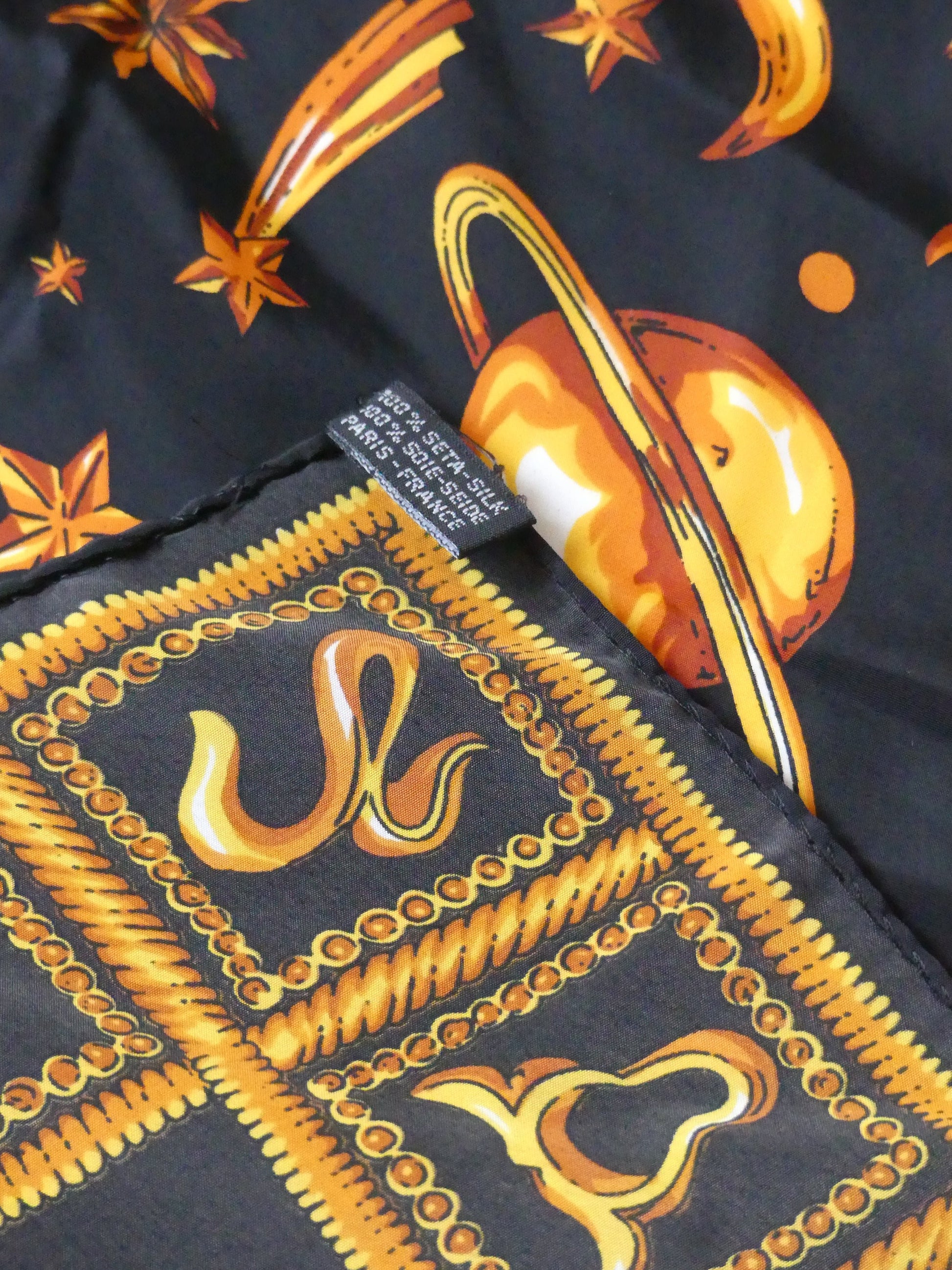 Elegant astrology silk scarf in black with golden celestial suns, stars, and planets, made in Paris from 100% silk – a luxurious holiday accessory or gift
