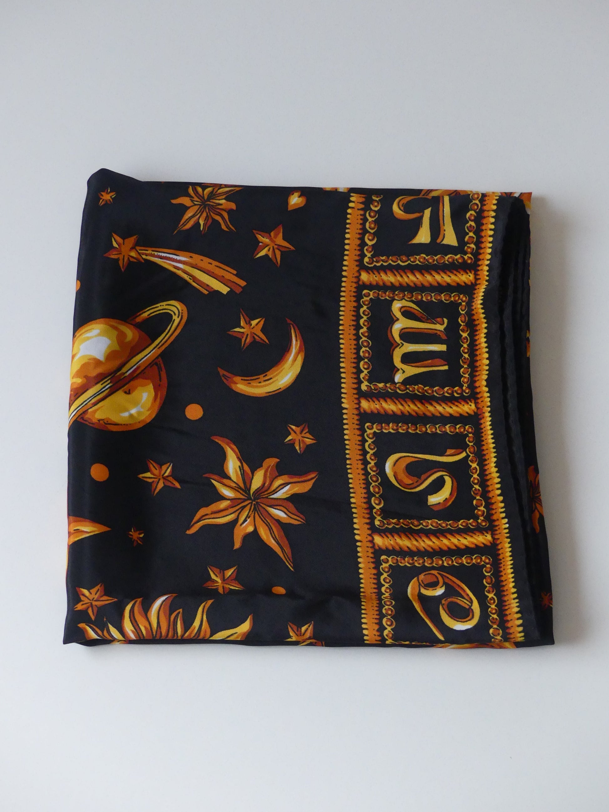 Discover the perfect holiday gift with our Astrology Silk Scarf, crafted in Paris from 100% silk. Featuring celestial suns, stars, and planets on elegant black, this timeless accessory exudes sophistication and cosmic charm. Shop now for Parisian-made luxury!